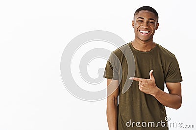 Waist-up shot of cheerful nice and handsome young african american man pointing left with index finger smiling and Stock Photo