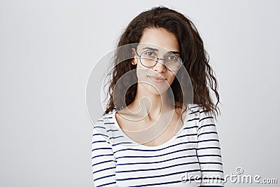 Waist-up shot of cute smart curly-haired girl in round glasses smiling broadly, being able to solve any riddle or issue Stock Photo