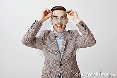 Waist-up shot of enthusiastic charming european male entrepreneur picking new glasses in optician store putting on round Stock Photo