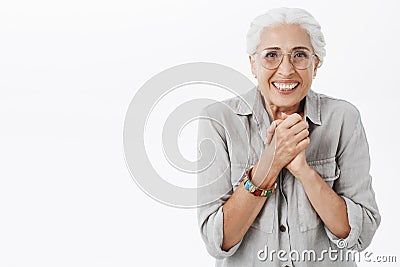Waist-up shot of excited enthusiastic and happy elderly woman in glasses and shirt clenching palms together over chest Stock Photo