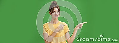 Waist-up shot of good-looking friendly and feminine female coworker in yellow t-shirt showing newbie office pointing and Stock Photo