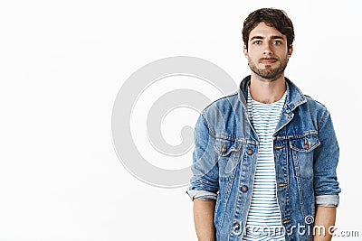 Waist-up shot of nice handsome guy in stylish denim jacket over striped t-shirt smirking shy and awkward as standing Stock Photo