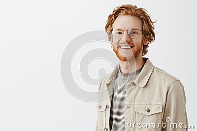 Waist-up shot of pleasant handsome redhead mature guy with beard in transparent glasses and beige jacket over t-shirt Stock Photo