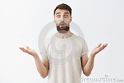 Waist-up shot of surprised and amazed good-looking stylish bearded male raising eyebrows shrugging with hands spread Stock Photo