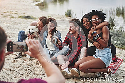 Wait, I`m focusing. Group of people have picnic on the beach. Friends have fun at weekend time Stock Photo