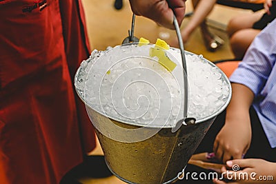 Waiter carrying a metal bucket full of ice to cool drinks in summer Stock Photo