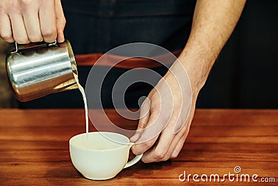 Waiter hands pouring milk making cappuccino Stock Photo
