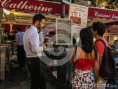 Waiter hovers while couple studies menu at Montmartre restaurant Editorial Stock Photo