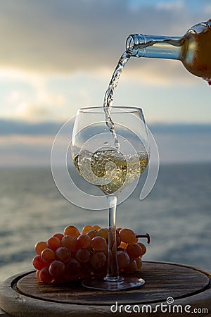 Waiter pouring aperitif white wine in glasses on outdoor tessace witn sea view Stock Photo