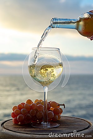 Waiter pouring aperitif white wine in glasses on outdoor tessace witn sea view Stock Photo