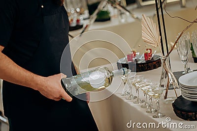 Waiter pouring martini or champagne in crystal glasses on table party at wedding reception Stock Photo