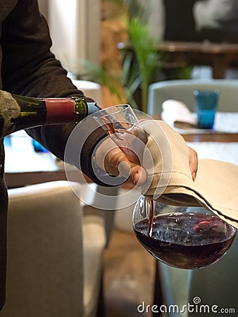 The waiter pours elite red wine into the decanter. Vertical orientation Stock Photo