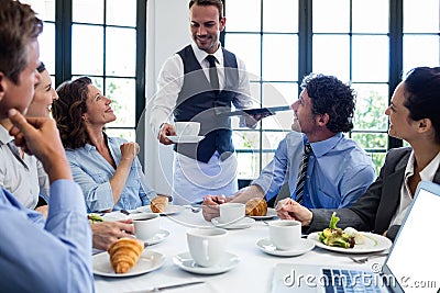 Waiter serving coffee to business people Stock Photo
