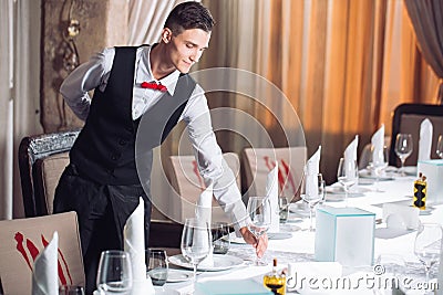 Waiter serving table in the restaurant preparing to receive guests. Stock Photo