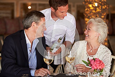 Waiter Serving Wine To Senior Couple In Restaurant Stock Photo