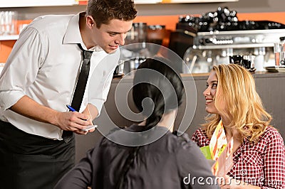 Waiter taking orders from young woman customer Stock Photo