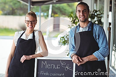 Waiter and waitress standing with menu board outside the cafe Stock Photo