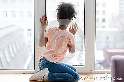 Waiting african american young girl sitting alone on windowsill., Stock Photo