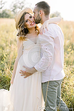 Waiting for the baby, pregnancy concept. Happy young couple, expecting a baby, walking in bright summer sunny day on a Stock Photo