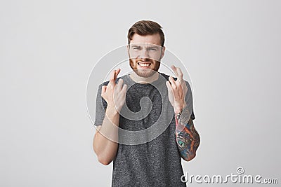 Waiting for competition results. Body language. Portrait of young attractive bearded tattooed male student with trendy Stock Photo