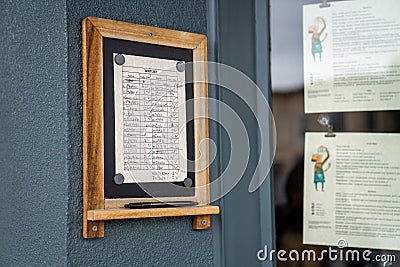 Waitlist filled out with names at popular restaurant next to menus Editorial Stock Photo