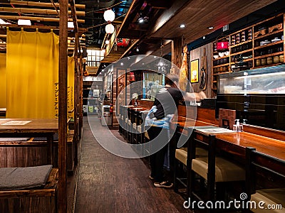 A waitress cleans the empty tables at The Public Izakaya Japanese restaurant in Tanjong Pagar, Singapore Editorial Stock Photo