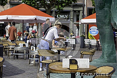 Waitress cleans a table on restaurant terrace with disinfectant alcohol spray Editorial Stock Photo