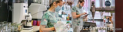 Waitress with mask cleaning glasses while her coworker works wit Stock Photo