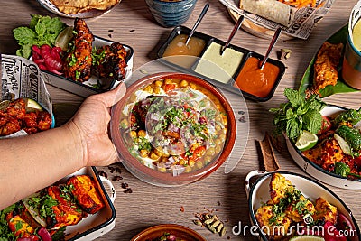 The waitress places the samosa chana chaat plate on the table. Culinary feast. Indian cuisine. Variety of dishes Stock Photo