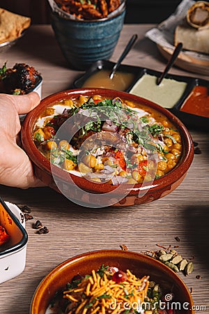 The waitress places the samosa chana chaat plate on the table. Culinary feast. Indian cuisine. Variety of dishes. Vertical image Stock Photo