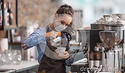 Waitress prepares capuccino in a cafe wearing protective face mask Stock Photo