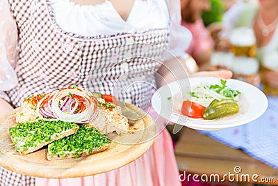 Waitress serving Bavarian food in beer garden Stock Photo