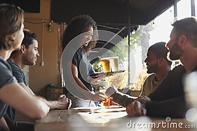 Waitress Serving Drinks To Group Of Male Friends Meeting In Sports Bar Stock Photo