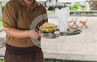 Waitress serving french fries in tray at restaurant outdoors. Stock Photo
