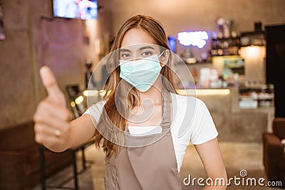 Waitress wearing a face mask at the coffee shop Stock Photo