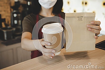 Waitress wearing protection face holding hot coffee cup and paper bag waiting for customer Stock Photo