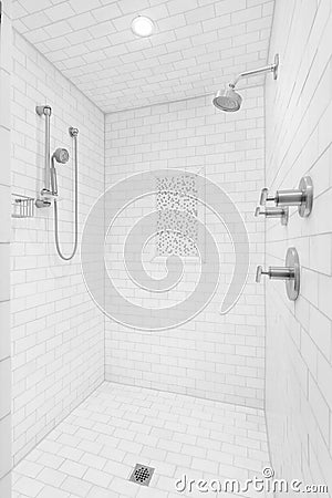 A walk-in shower with white subway tiles and chrome showerhead. Stock Photo