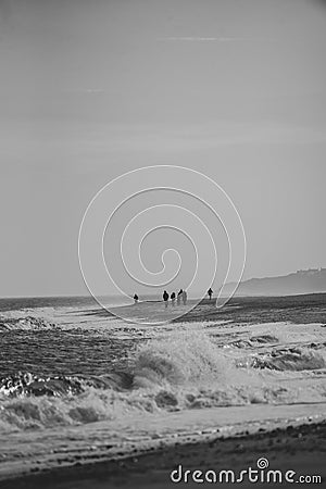 Walkers on a beach in winter Stock Photo