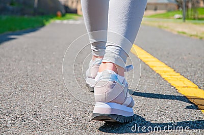 Walking. Close-up of women`s running shoes on a paved trail. Stock Photo