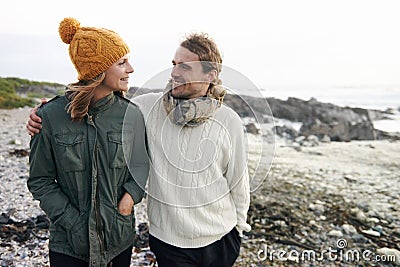 Walking, love and couple by ocean in winter for bonding, romantic relationship and relax outdoors. Marriage, travel and Stock Photo