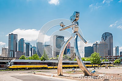 Walking man statue Dallas Texas with skyline and train Editorial Stock Photo