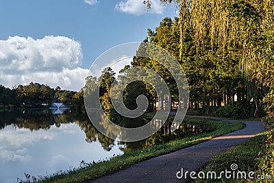 Walking Path by Lake with Fountian and Reflections off Water Stock Photo