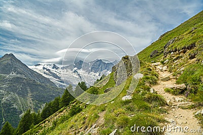 Walking trail from Kreuzboden to Saas-Almagell with incredible views on always white Alps above the Saas-Fee village in Stock Photo