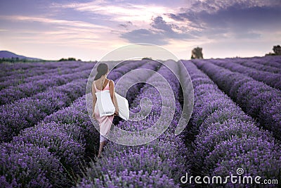 Walking women in the field of lavender.Romantic women in lavender fields. Girl admires the sunset in lavender fields. Stock Photo