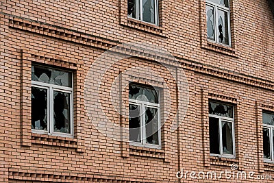 The wall of an abandoned brick house with broken glass in the Windows. The concept of chaos Stock Photo