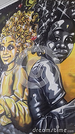 Wall art graffiti of 2 Afro caribbean people 1 Black the other yellow. Editorial Stock Photo