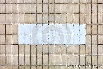 On the wall, covered with old rectangular tiles, the selected fragment is painted with white paint Stock Photo