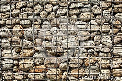 Wall made of round rocks, secured with steel wire net iron ston Stock Photo