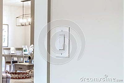 Wall mounted electrical rocker light switch with blurry dining room background Stock Photo