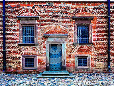 wall of the old red brick with dark door and symmetrical windows Stock Photo